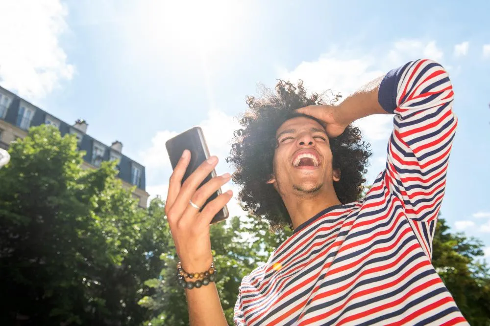 Cheerful Young Arabic Man Laughing With Mobile Phone