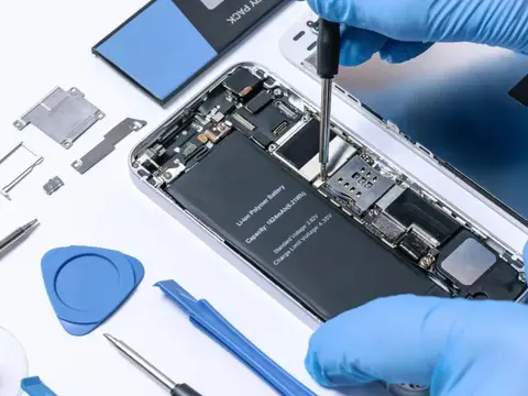 Technician repairing a smartphone with tools on a workbench